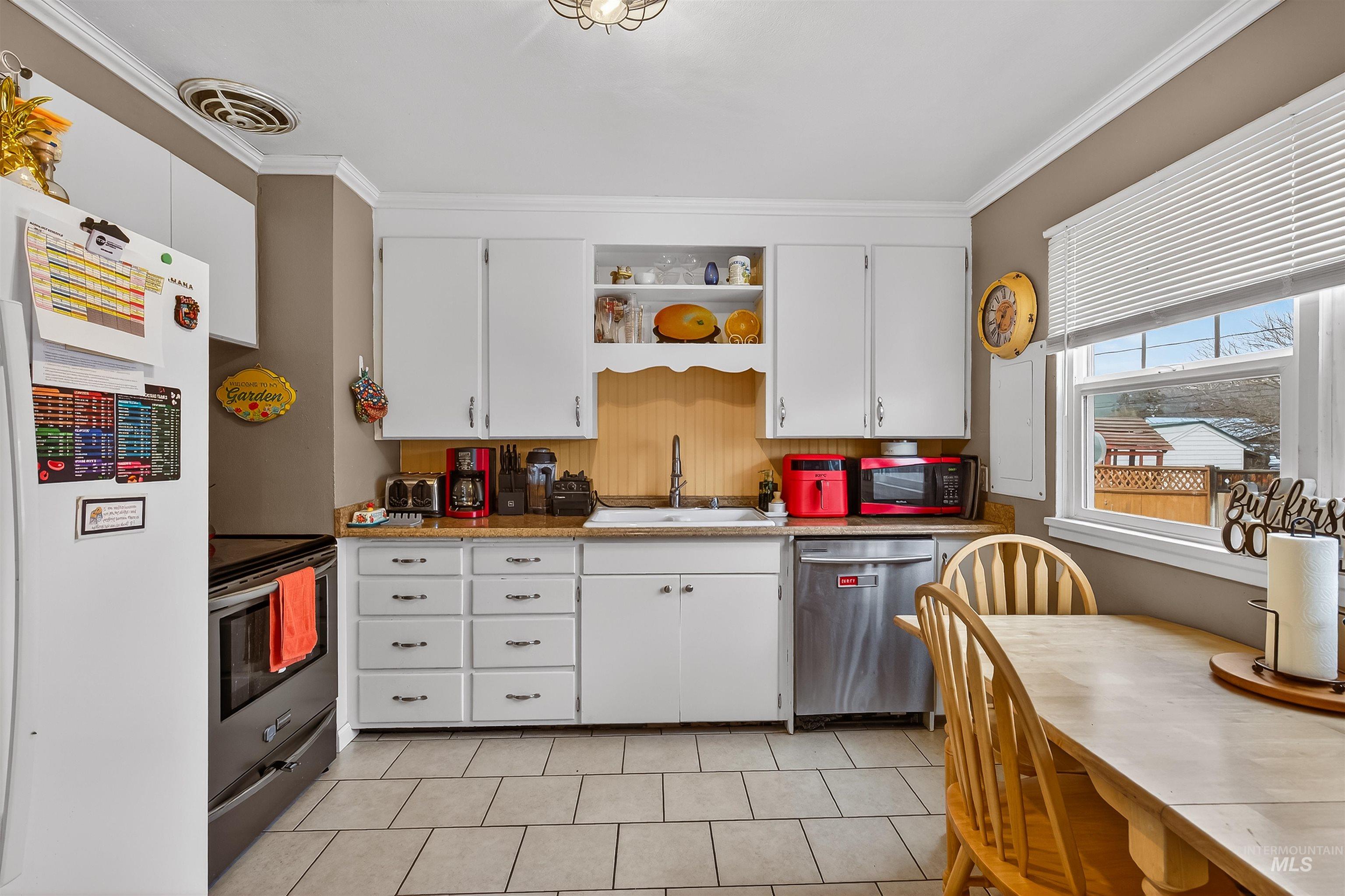 835 12th Street Clarkston, WA 99403 - Photo 13 of 39 Kitchen featuring white cabinets, stainless steel appliances, open shelves, ornamental molding, and light countertops