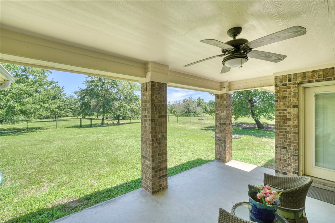 9945 Oxford Cemetery Road Madisonville, TX 77864 - Photo 25 of 42 Fenced backyard with a patio, a ceiling fan, and view of scattered trees