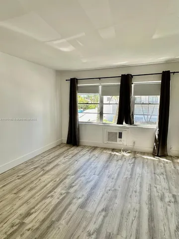 a big room with wooden floor and windows in a room