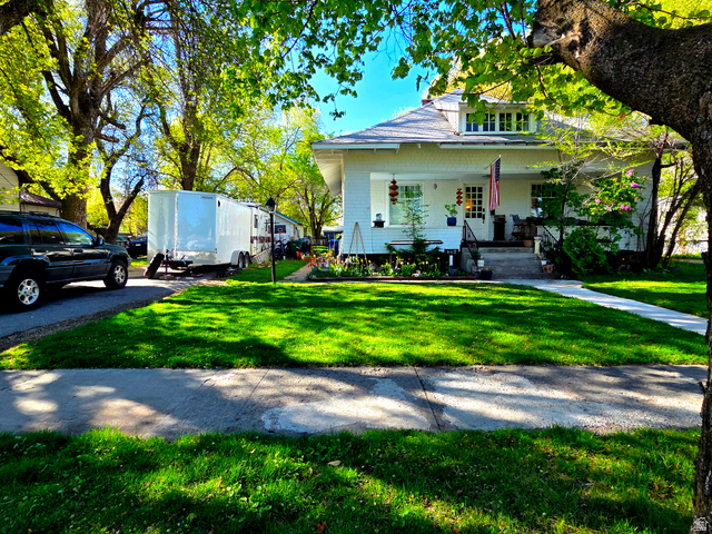 142 West 400 North Logan, UT 84321 - Photo 6 of 35 White-sided residence with dormer windows, a covered front porch, and a concrete walkway