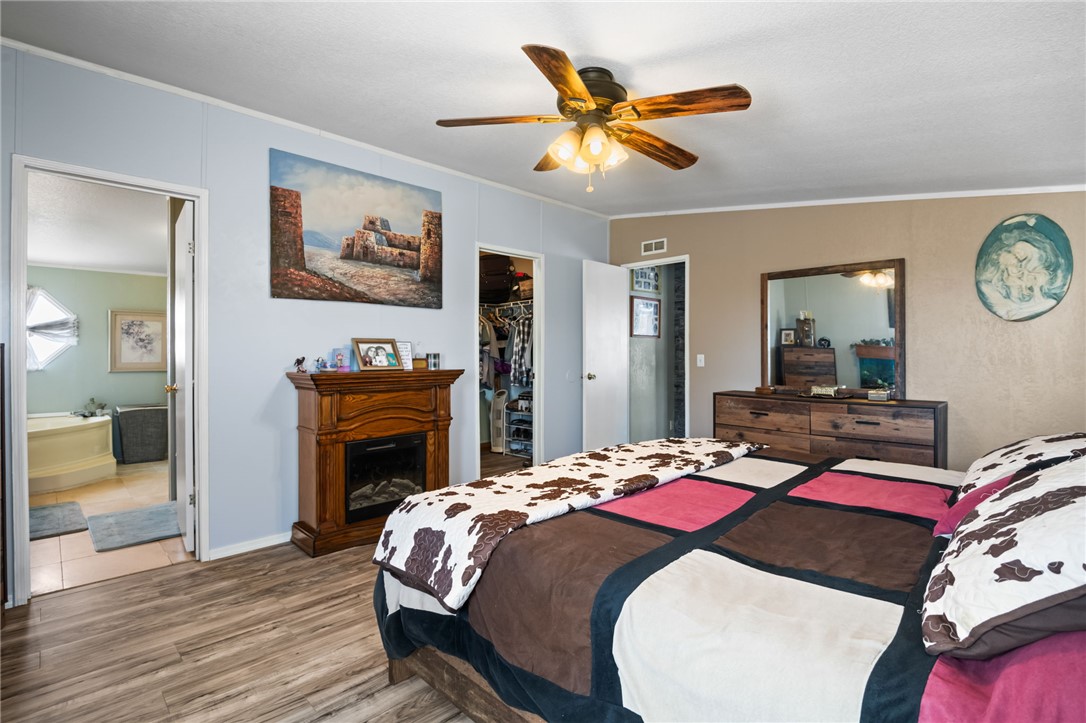 3411 Mayer Road Golden Valley, AZ 86413 - Photo 14 of 49 Bedroom featuring crown molding, wood finished floors, a spacious closet, a ceiling fan, and connected bathroom