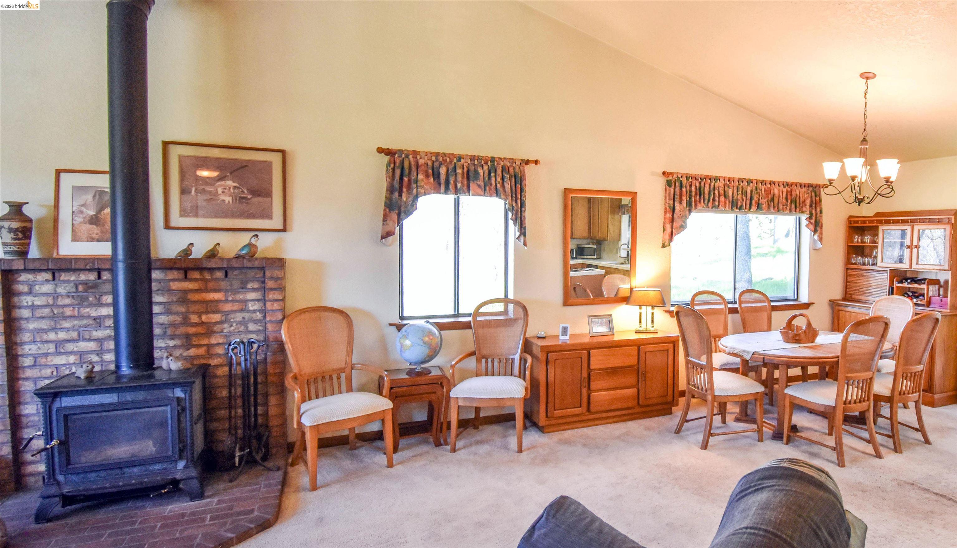 15170 Potato Ranch Road Sonora, CA 95370 - Photo 8 of 49 Dining room with a wood stove, carpet floors, suspended lighting, and lofted ceiling