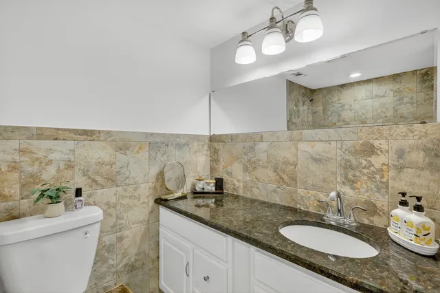 a bathroom with a granite countertop sink a toilet and a mirror