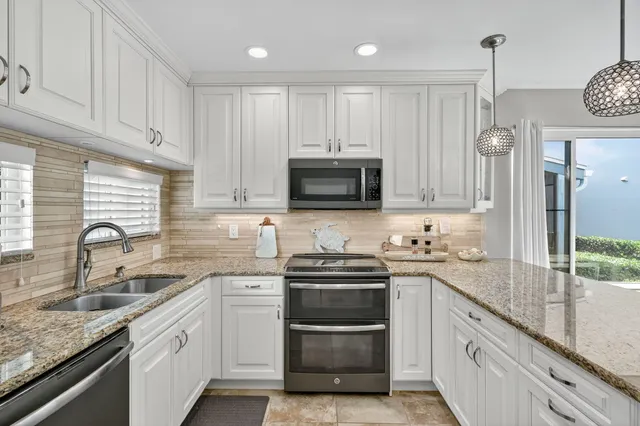 a kitchen with granite countertop white cabinets and stainless steel appliances