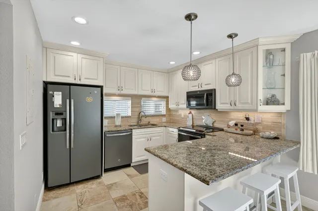 a kitchen with stainless steel appliances granite countertop a sink refrigerator and cabinets