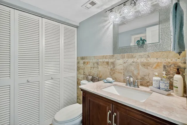 a bathroom with a granite countertop sink vanity mirror and toilet