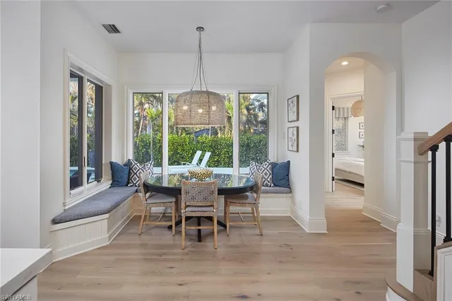 a dining room with wooden floor a chandelier a glass table and chairs