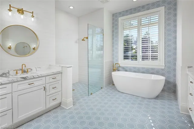 a spacious bathroom with double vanity sink a two mirror a window a bathtub and vanity