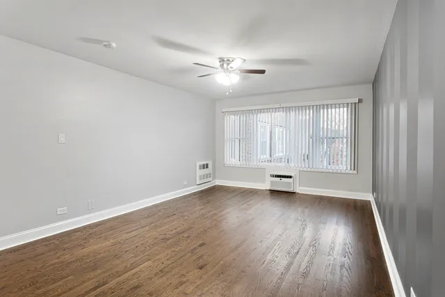 an empty room with wooden floor ceiling fan and windows