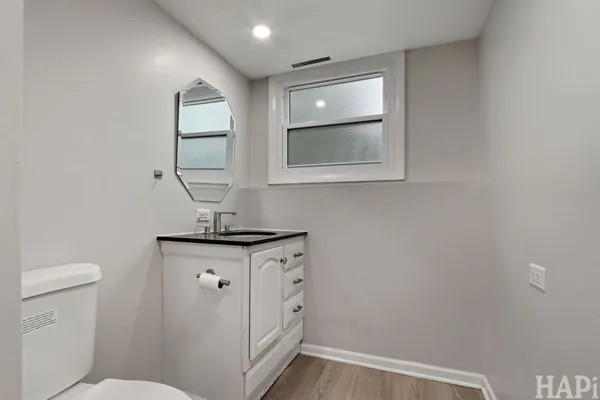 a bathroom with a granite countertop toilet sink and mirror