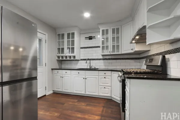 a kitchen with stainless steel appliances granite countertop a refrigerator a stove and a sink