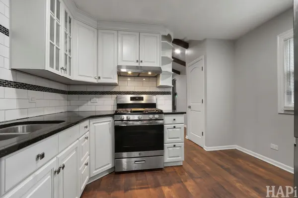 a kitchen with granite countertop white cabinets and stainless steel appliances