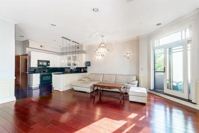 a living room with couches and kitchen view with wooden floor