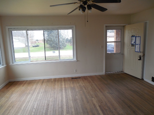5925 Island Road Harvard, IL 60033 - Photo 7 of 22 an empty room with wooden floor fan and windows