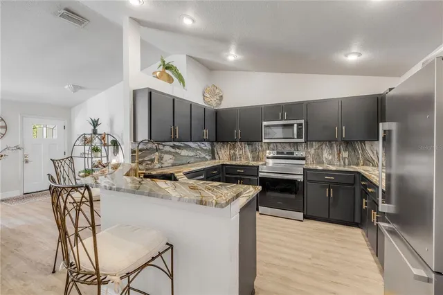 a kitchen with refrigerator a sink and chairs