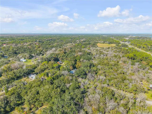 an aerial view of residential houses with outdoor space and trees