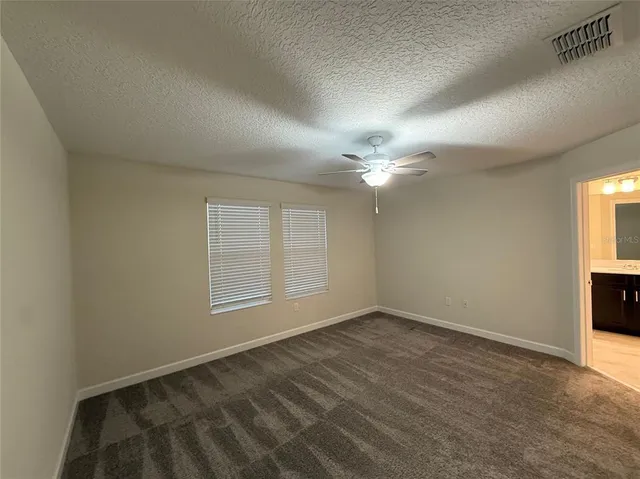 an empty room with windows and fan