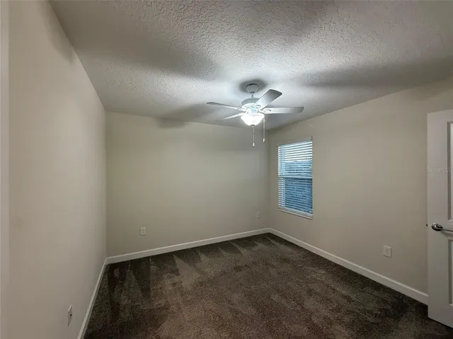 an empty room with a chandelier fan and windows