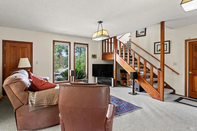 a living room with furniture stairs and a large window