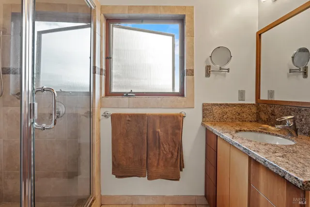 a bathroom with a granite countertop sink a mirror and shower