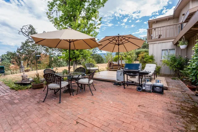 a view of patio with chairs and table under an umbrella