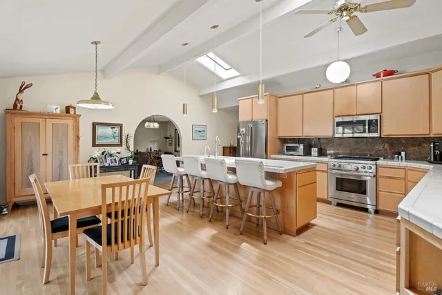 a kitchen with stainless steel appliances a stove a sink a dining table and chairs