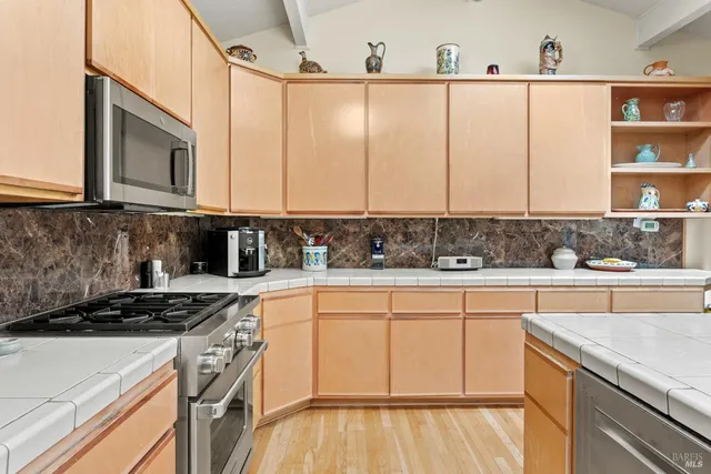 a kitchen with stainless steel appliances granite countertop a stove a sink and white cabinets
