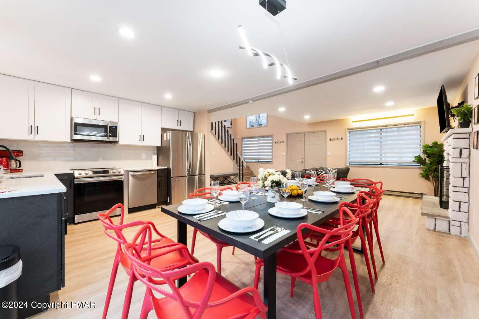 a open dining room with stainless steel appliances kitchen island granite countertop a dining table chairs and a refrigerator