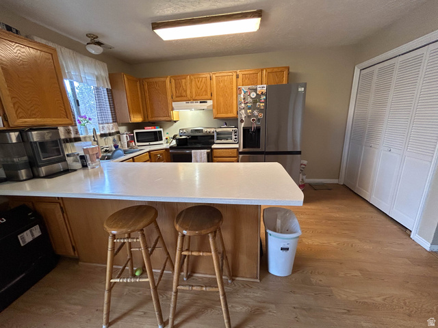 939 South Freedom Boulevard, Unit 13 Provo, UT 84601 - Photo 9 of 26 Kitchen featuring stainless steel appliances, light countertops, light wood-style floors, a kitchen breakfast bar, and a peninsula