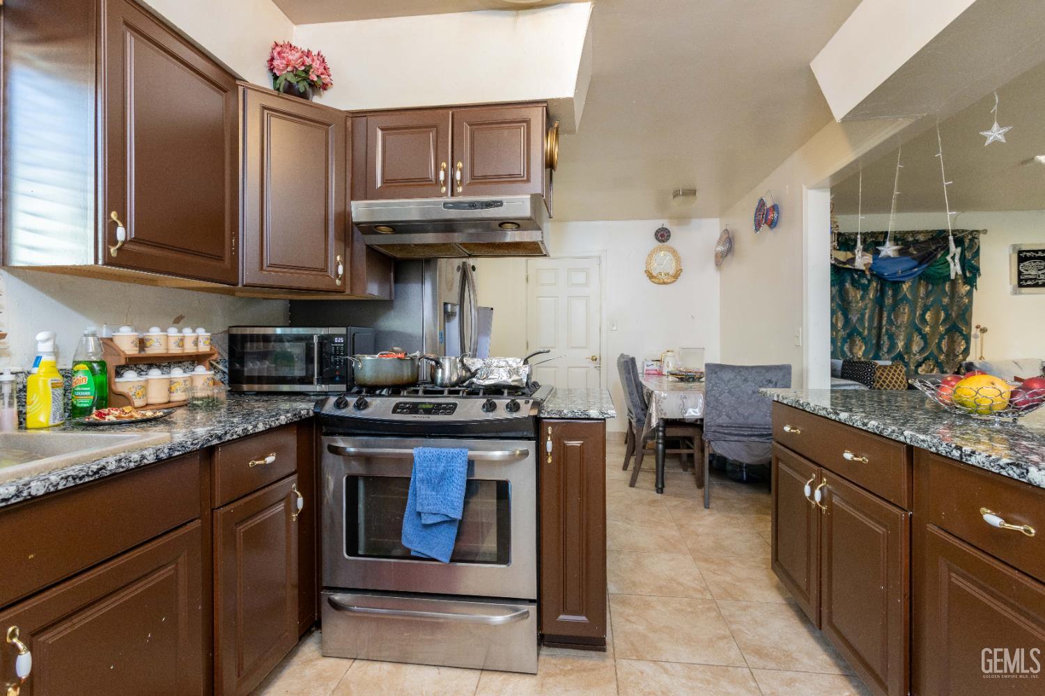 Undisclosed Address Delano, CA 93215 - Photo 12 of 35 a kitchen with stainless steel appliances granite countertop a sink stove and cabinets