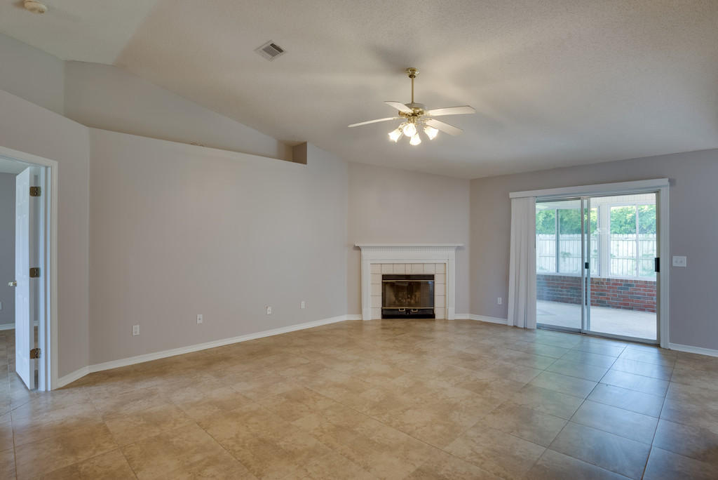 1969 Jessica Way Navarre, FL 32566 - Photo 4 of 17 an empty room with windows fireplace and fan