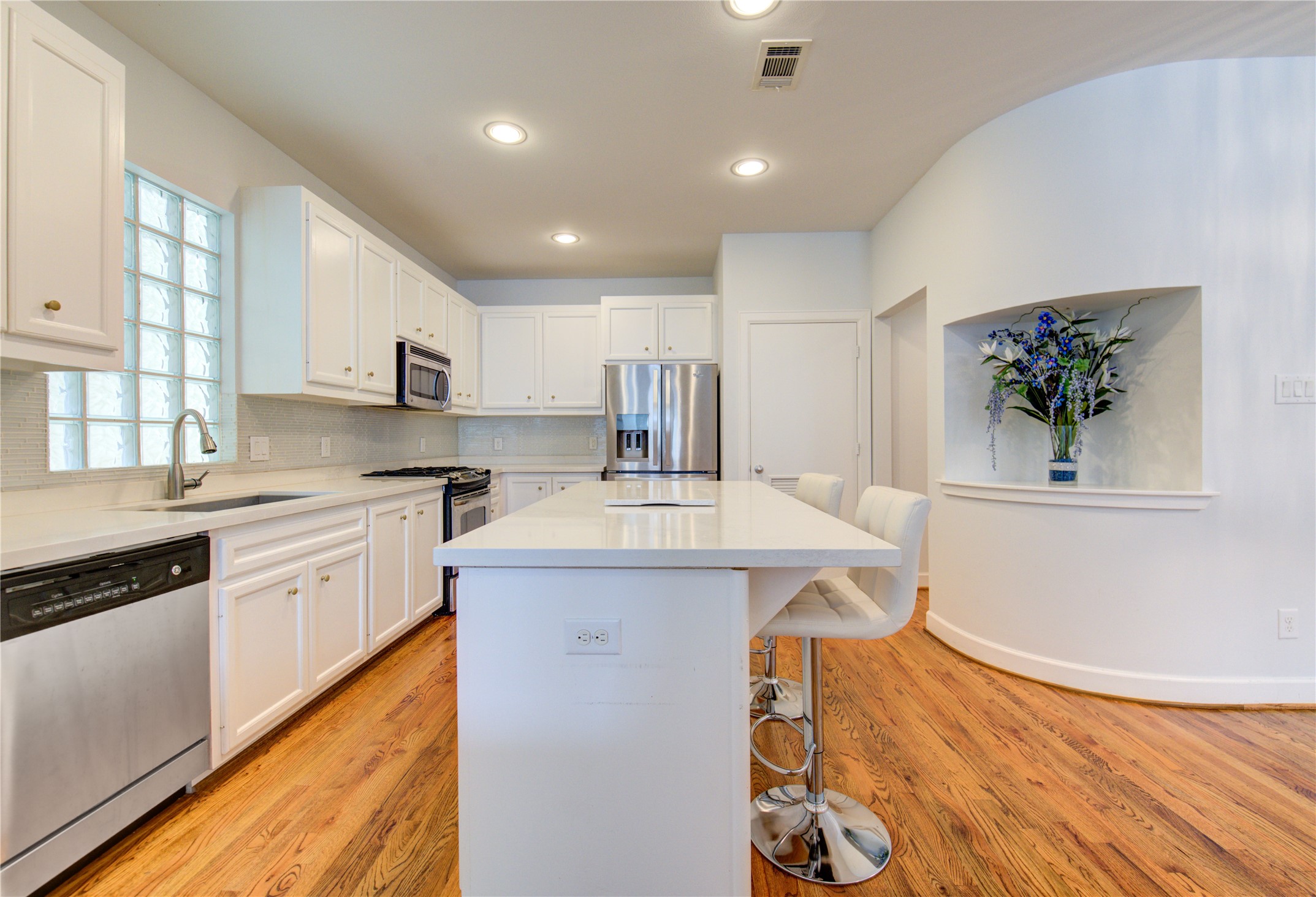 650 Westcross Street, Unit 83 Houston, TX 77018 - Photo 20 of 48 a kitchen with kitchen island a stove a sink a refrigerator and a dining table with wooden floor