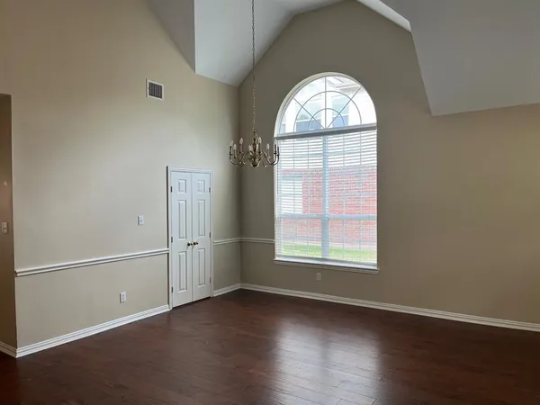 an empty room with wooden floor windows and entrance