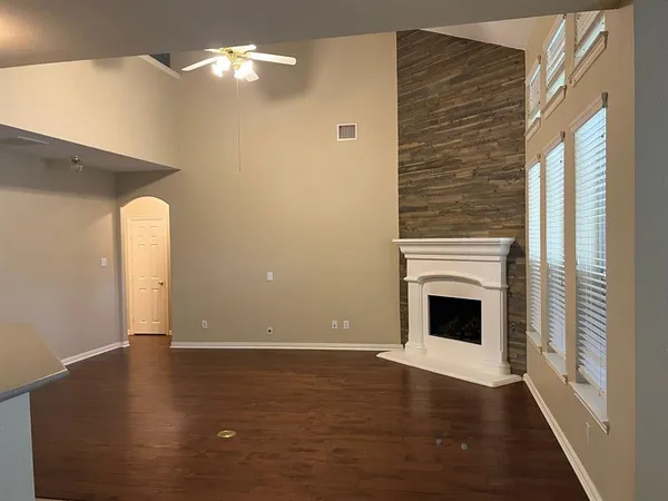 a view of a livingroom with wooden floor a ceiling fan and windows