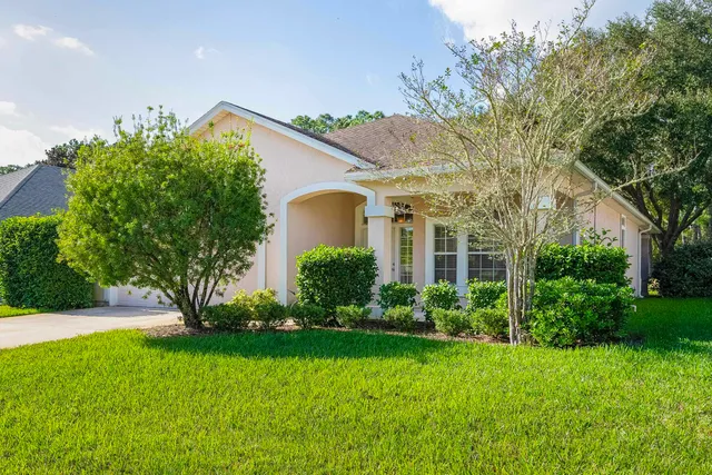 a view of a house with a yard and a large tree