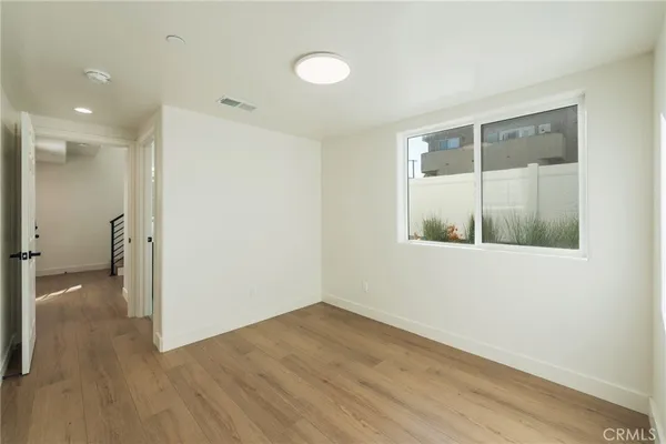 a view of a hallway with wooden floor and a bathroom