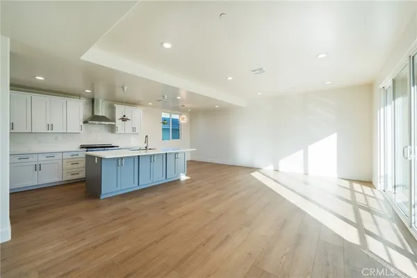 a large kitchen with a large counter top a sink stainless steel appliances and cabinets