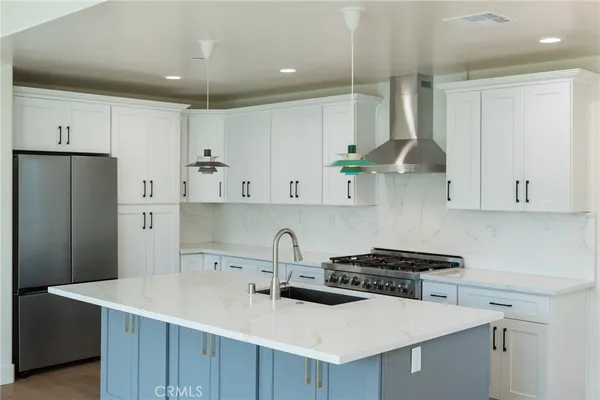 a kitchen with stainless steel appliances a sink a stove a refrigerator and cabinets