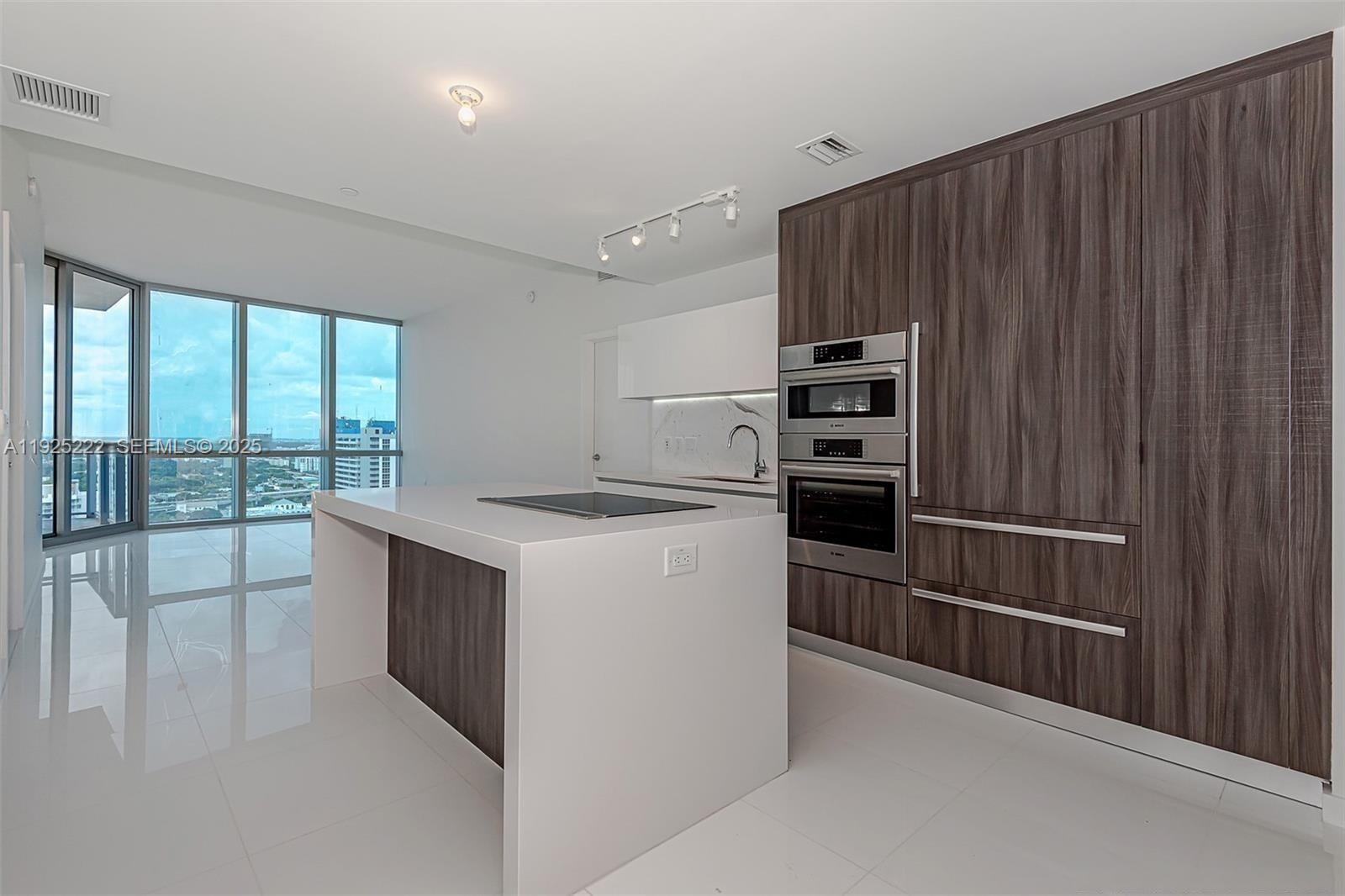 851 Northeast 1st Avenue, Unit 1608 Miami, FL 33132 - Photo 1 of 34 a kitchen with kitchen island wooden cabinets and stainless steel appliances
