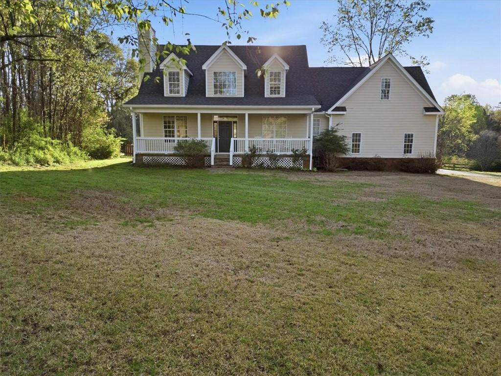 a view of a white house next to a yard with big trees