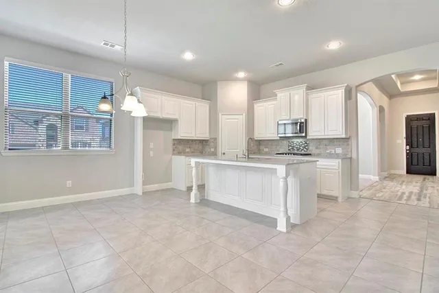 a view of an empty room with kitchen and fireplace