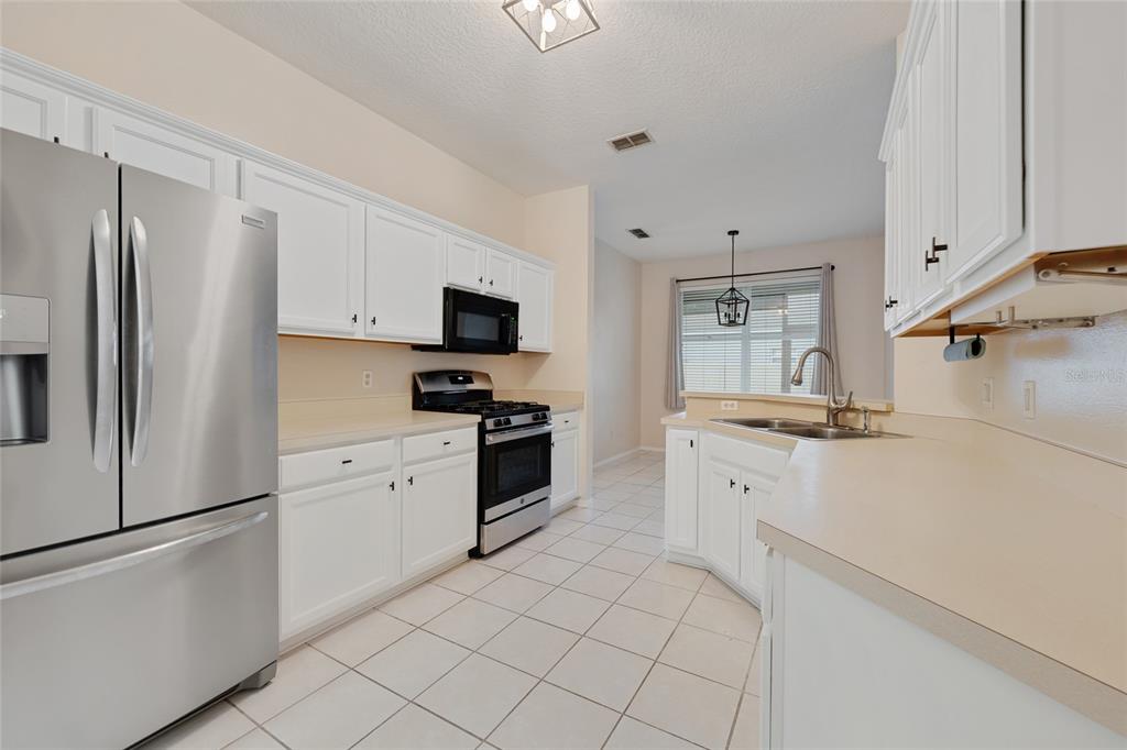 1073 Turtle Lake Court Ocoee, FL 34761 - Photo 23 of 46 a kitchen with white cabinets stainless steel appliances and a refrigerator
