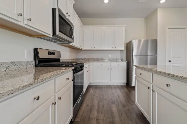 a kitchen with stainless steel appliances granite countertop a stove a sink and a microwave