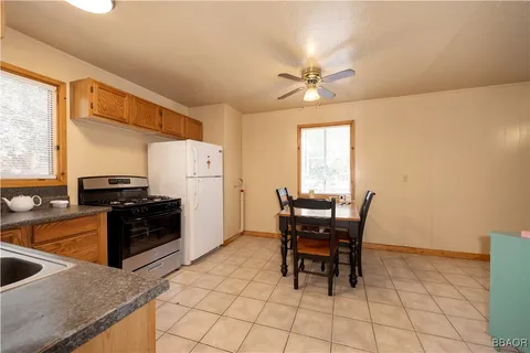 a kitchen with stainless steel appliances granite countertop a stove a refrigerator a sink a dining table and chairs with wooden floor