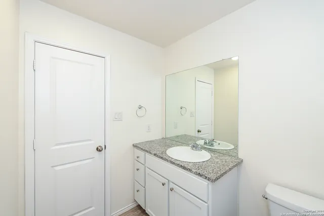 a bathroom with a granite countertop sink toilet a mirror and shower