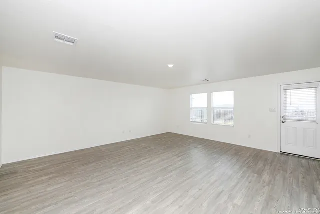 an empty room with wooden floor and windows