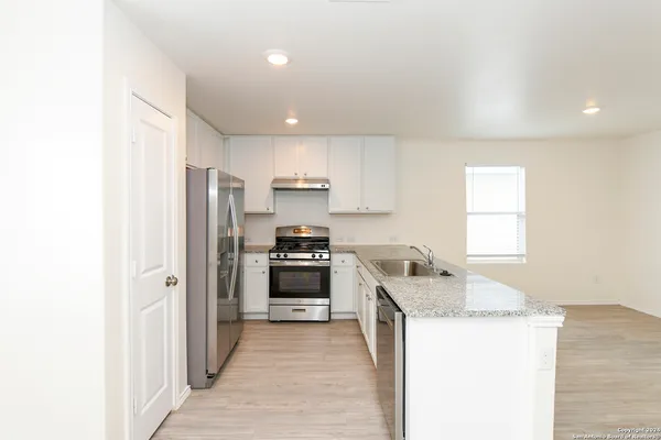 a kitchen with granite countertop a sink stove and refrigerator