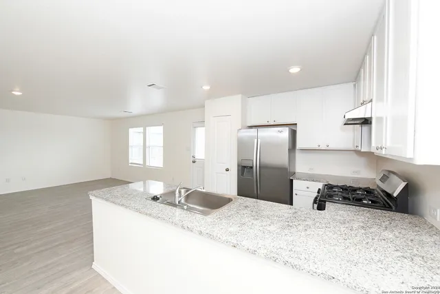 a kitchen with stainless steel appliances granite countertop a sink refrigerator and stove