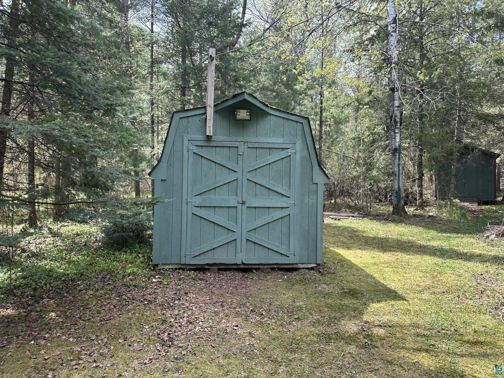 81 Hautaluoma Road Esko, MN 55733 - Photo 41 of 43 Barn-style shed with double doors, featuring a gabled roof and exterior lighting