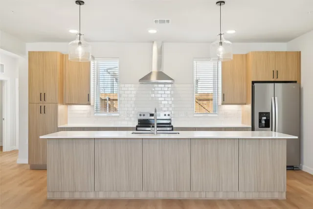 a kitchen with kitchen island granite countertop a stove a refrigerator and a chandelier
